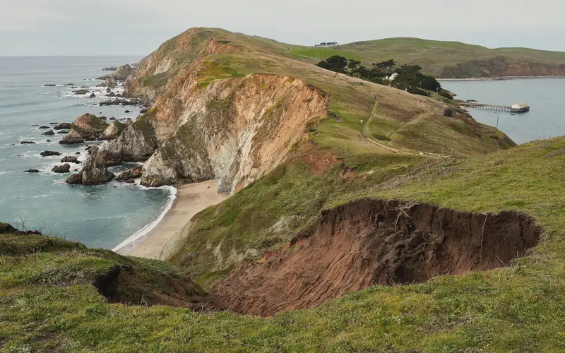 Photo of green headlands and a sandy cove seen from Chimney Rock at Point Reyes